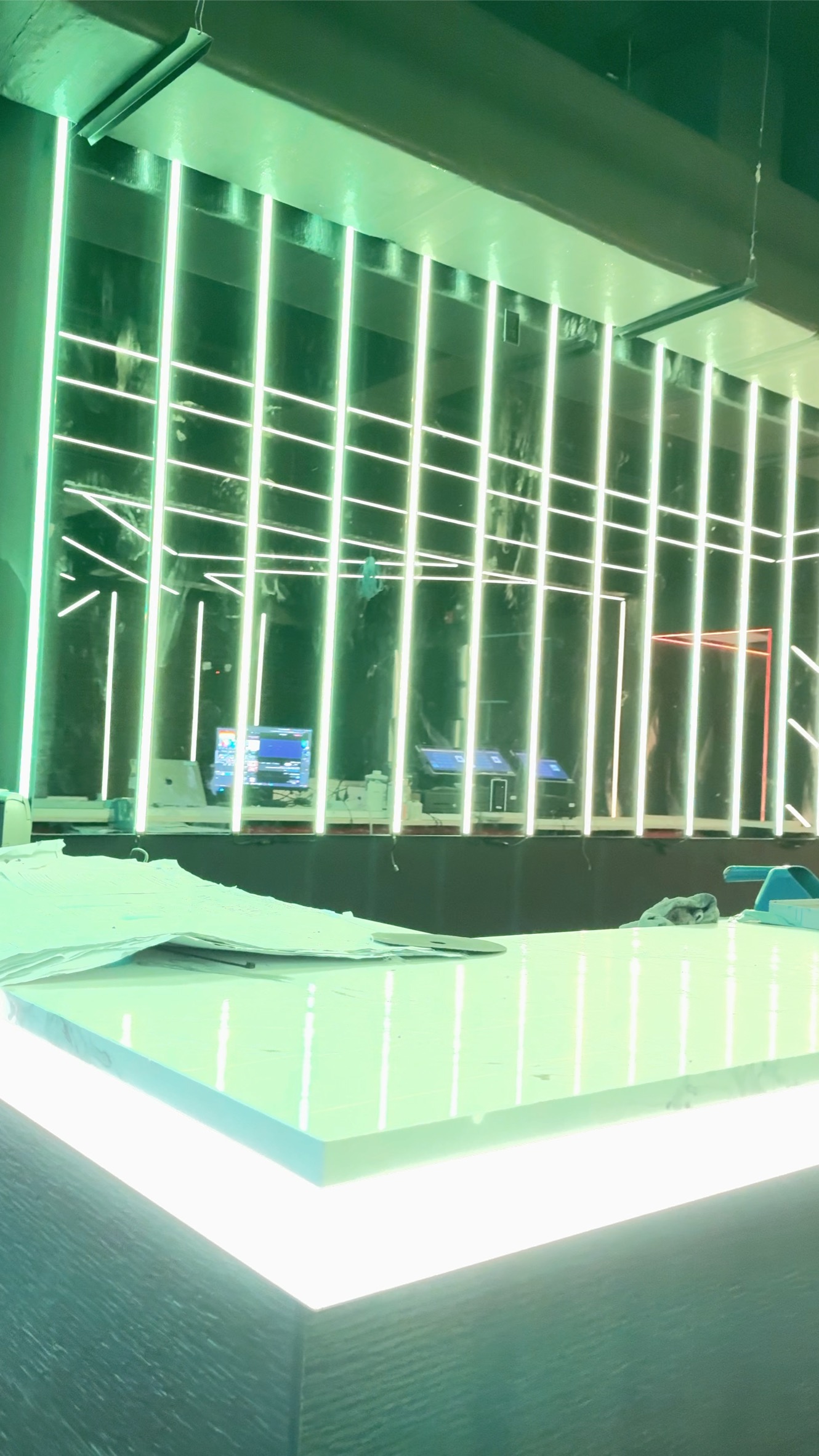 Green vertical light bars reflected in mirrors above the illuminated bar counter at Anthem Orlando