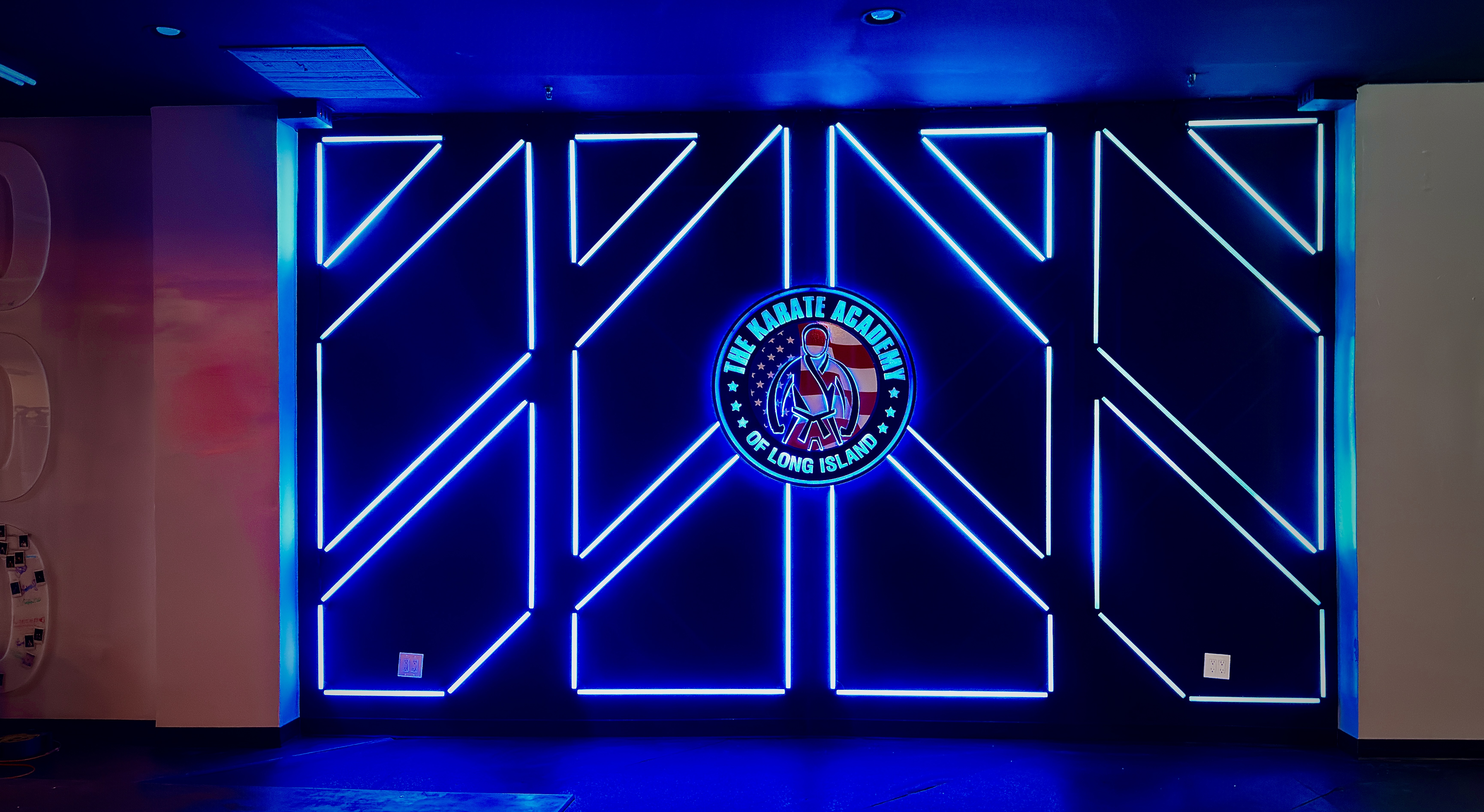 Blue and cyan geometric light across the academy feature wall