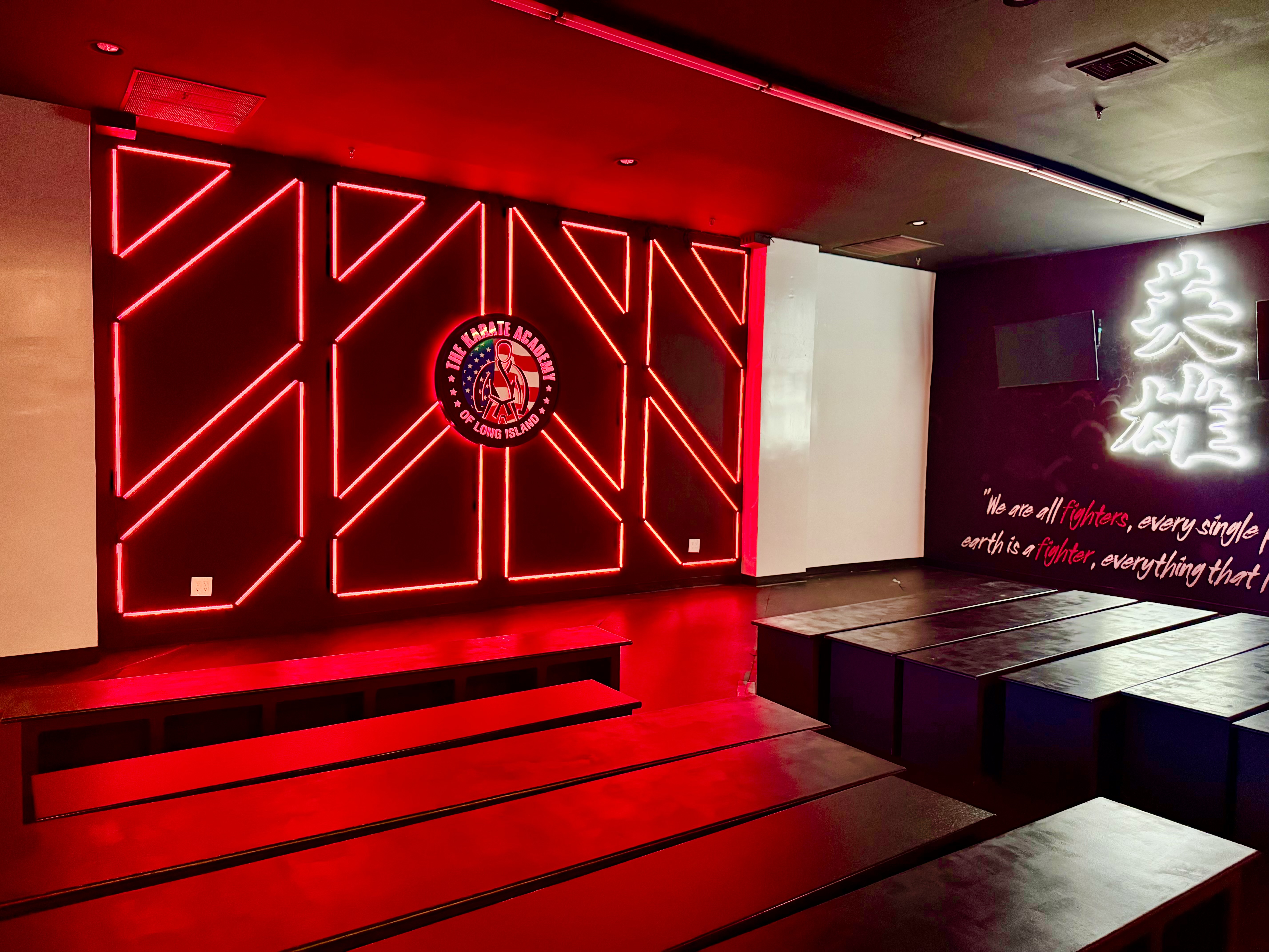 Red feature-wall lighting beside illuminated wall lettering at The Karate Academy of Long Island