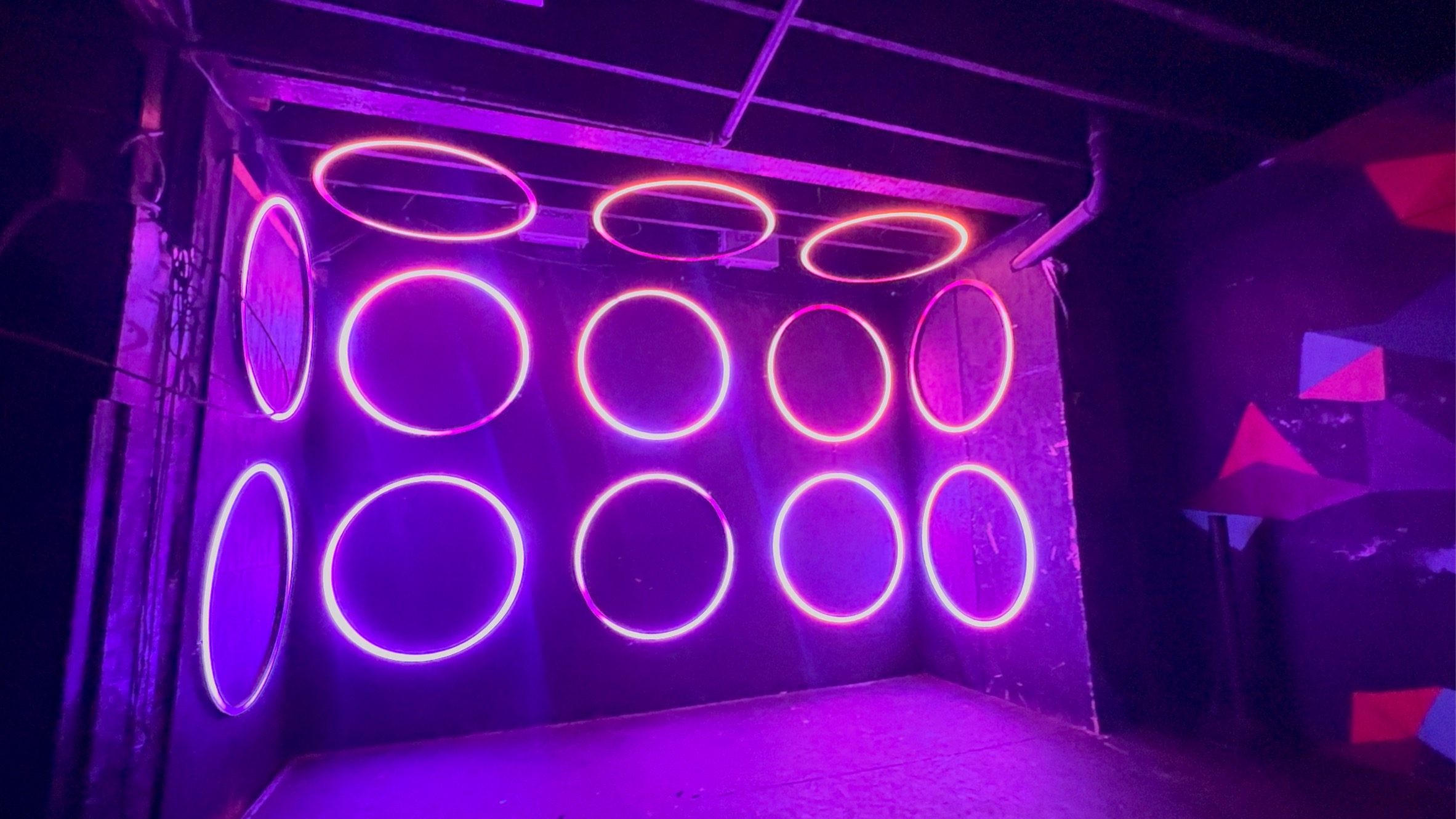 Room with walls of glowing magenta and violet LED rings