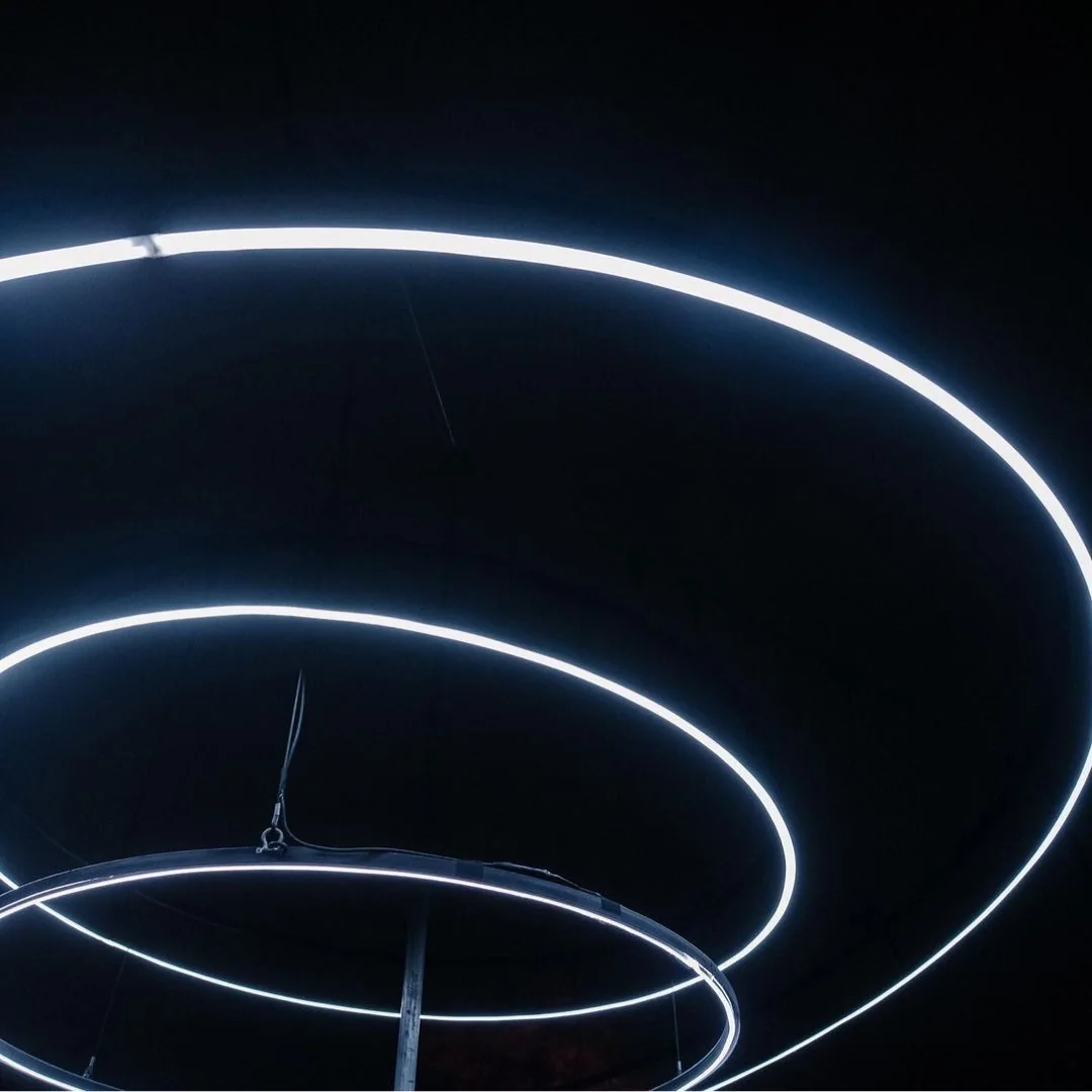 Three suspended white LED halo rings floating in a dark ceiling